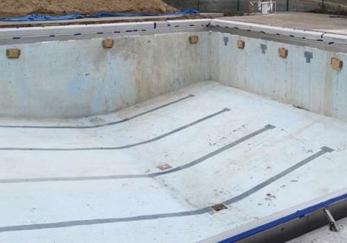 Bazén před rekonstrukcí - bílý s prohlým dnem směřujícím vzhůru, vypuštěný a se sundanou stávající fólií