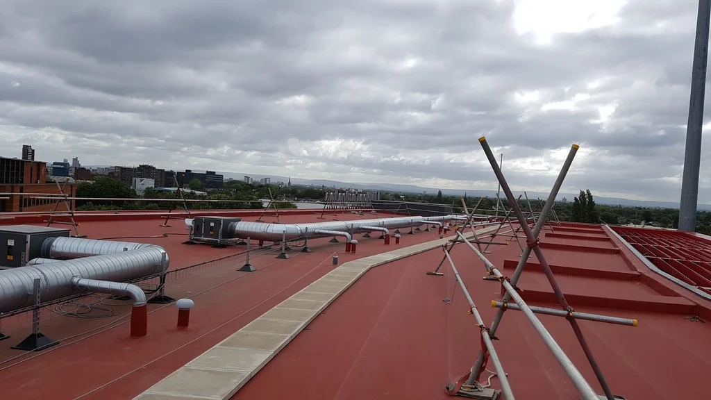 Červená střecha hotelu Hilton Garden Inn s fólií Protan SE a ventilačními rozvody, v pozadí panorama Manchesteru.